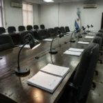 Empty provincial legislative committee room with unsigned documents on the table