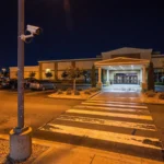 Night view of a casino entrance crosswalk and parking lot with a surveillance camera on a pole