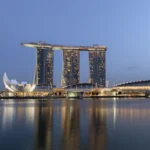 Marina Bay waterfront in Singapore at dusk with integrated resort towers reflected in the water