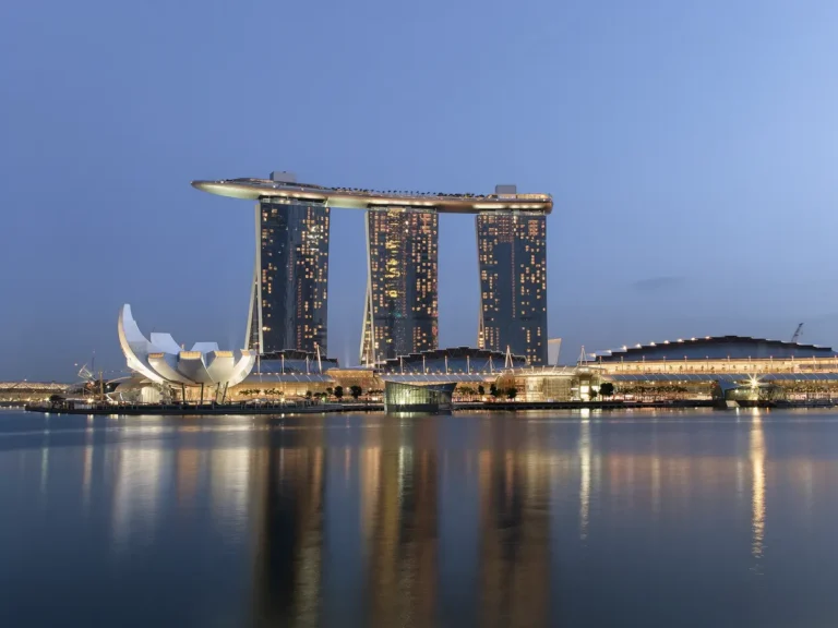 Marina Bay waterfront in Singapore at dusk with integrated resort towers reflected in the water