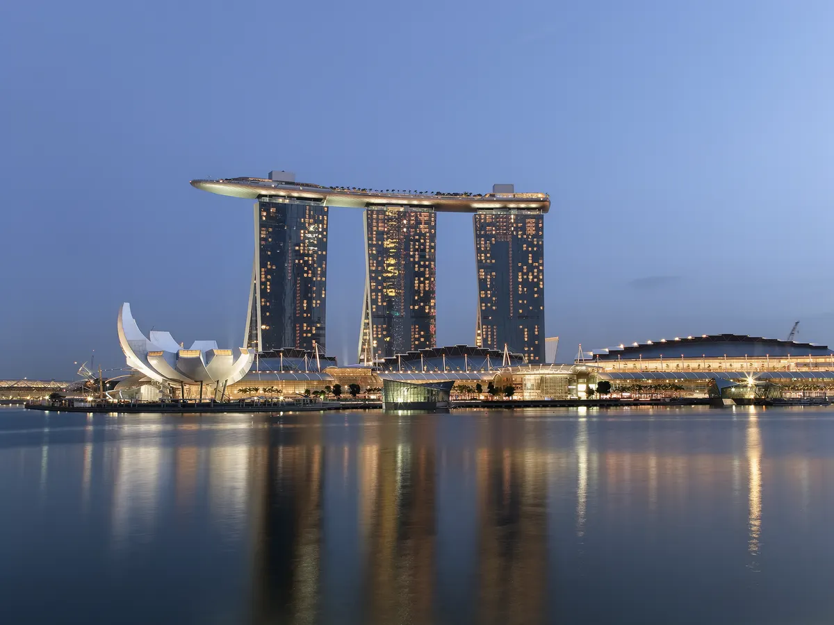 Marina Bay waterfront in Singapore at dusk with integrated resort towers reflected in the water